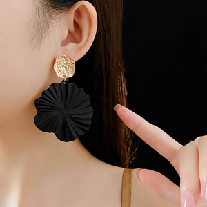 Detail of gold geometric stud and black textured floral pendant earring on model