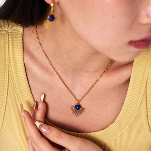Close-up of model wearing gold sunburst jewelry set with blue lapis lazuli gemstones