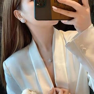 Elegant silver clover jewelry set with sparkling stones worn by model in white suit