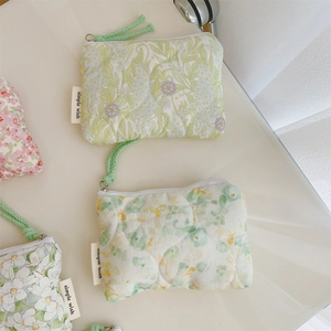 Close-up of floral quilted cotton pouch with zipper and simple wish woven label