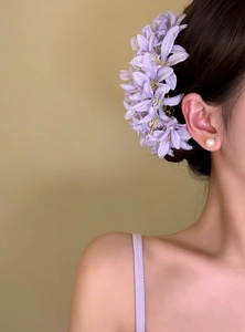 Side view detail of an elegant purple fabric flower hair fork on an Asian model