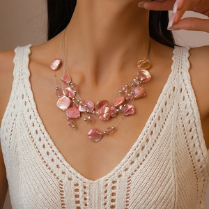 Detail of layered necklace featuring pink irregular shell slices and crystal beads
