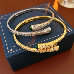 Detail of gold and silver plated open bangles with green gemstones and pavé crystals