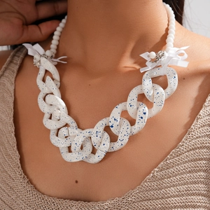 Detail of white acrylic chunky chain necklace with blue ink spots and ribbon bow