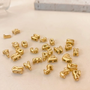Macro shot of gold vintage bubble alphabet beads and heart charms for jewelry making