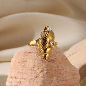 Detailed macro shot of golden shell-shaped ring with pearl and diamonds on natural rock