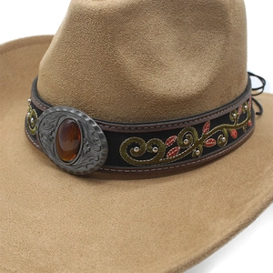Close-up of khaki suede cowboy hat featuring vintage bull head gem and vine embroidery