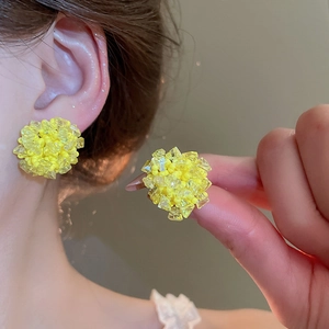 Macro detail of yellow crystal bead cluster earrings with silver needle on a model