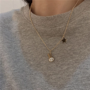 Close-up of golden bear pendant necklace with white shell detail on a gray sweater