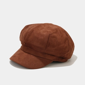 Detailed texture of brown faux suede newsboy cap with retro stitched panels and curved brim