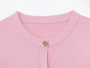 Dettaglio dello scollo del cardigan rosa in maglia con bordi a coste e bottone d'oro