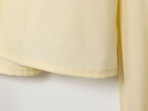 Detailed close-up of the fine stitching and woven texture on this yellow poplin shirt