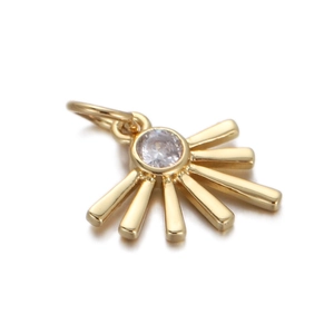 Macro shot of sunburst gold pendant with central clear zircon stone and metallic luster