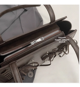 Detail of silver smooth zipper and woven strap on brown faux suede shoulder bag