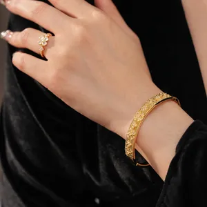 Gold plated floral bangle and ring set with zircon accents on black velvet background