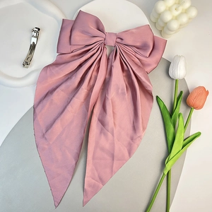 Vue détaillée d'une pince à cheveux en satin rose poudré avec de longs rubans élégants