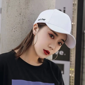 White baseball cap with grl Pwr embroidery and silver hoop earrings on fashion model