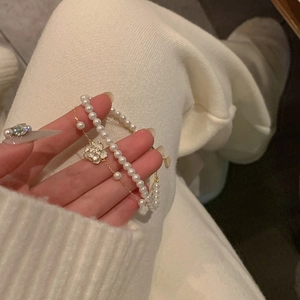 Detalle de la pulsera de perlas con colgante de camelia dorada y acabado de esmalte