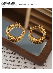 Detailed view of gold twisted rope hoop earrings on a mirror with elegant reflections