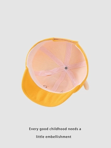 Detail view of the yellow corduroy baby hat showing pink inner lining and reinforced straps
