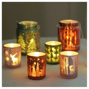Close-up of glass Christmas candle holders with reindeer and forest silhouette patterns