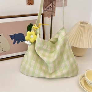 Detail of light green plaid canvas bag featuring a cute yellow flower plush charm accessory