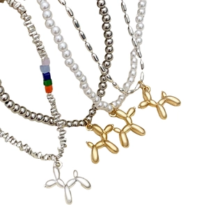 Dettaglio collana di perle a strati con perline metalliche e ciondolo cane palloncino
