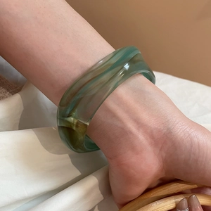 Detail of amber and green gradient acrylic resin bracelet with smooth curved surface