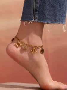 Detail view of a gold plated snake chain anklet with coin charms and geometric pendants