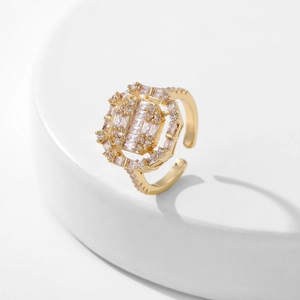 Close-up of golden octagonal open ring with clear cubic zirconia stones on white background