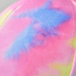 Macro shot of cotton tie-dye fabric with pink and blue gradient and neat stitching detail