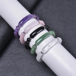 Multiple natural crystal bracelets with quartz and obsidian beads on a white display