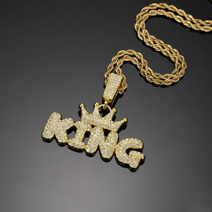 Close-up of gold KING crown pendant with iced-out crystals on a twist rope chain