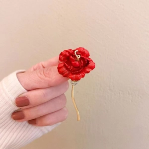 Close-up of elegant red flower brooch with gold stem and sparkling crystal accents