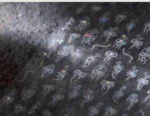 Detailed macro view of 3D embossed nail stickers featuring white bows and floral patterns