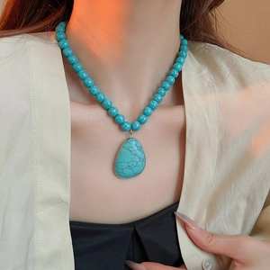 Detail view of Bohemian teardrop stone pendant with turquoise texture and beaded chain