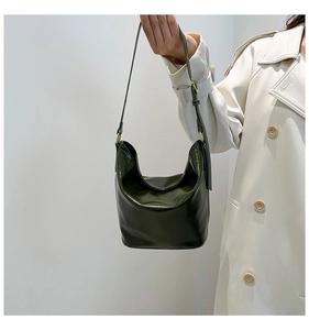 Detail of dark green glossy bucket bag with golden hardware and adjustable strap