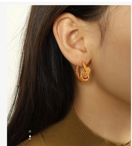 Détail des boucles d'oreilles nœud doré de style vintage français portées par un modèle