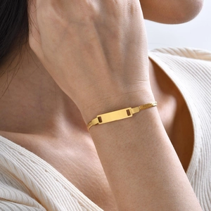 Close-up of a gold stainless steel flat snake chain bracelet with a blank bar pendant