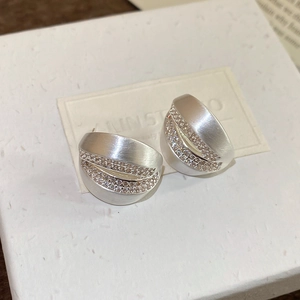 Detailed macro view of 18K brushed metal C-shape stud earrings with double row zircon stones