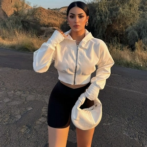 Detail of white cropped zip-up hoodie paired with high-waist biker shorts in sunset light