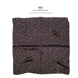 Detail of silk neck scarf featuring orange polka dots on a dark brown background
