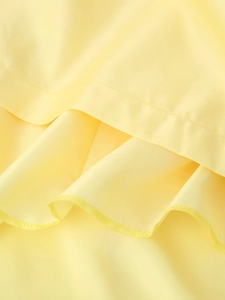 Close-up of yellow satin dress featuring delicate stitching and ruffled hem detail