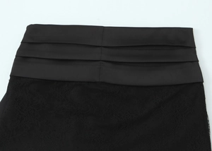 Detail of black lace mini skirt featuring a pleated satin waistband and delicate texture
