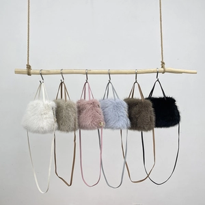 Faux fox fur crossbody bags in six colors hanging on a rustic wooden branch display