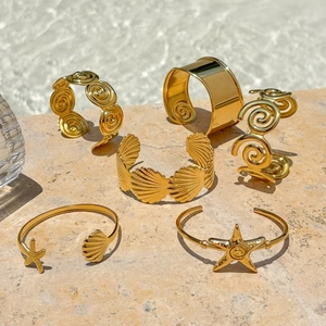 Macro detail of six 18K gold plated ocean theme bracelets with starfish and shell charms