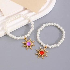 Close-up of pearl bracelets with golden sun pendants and colorful gemstone insets