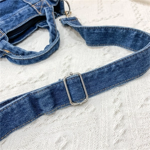 Detail of adjustable metal buckle and blue denim strap on a minimalist casual shoulder bag