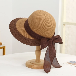 Detailed shot of two-tone woven sun hat featuring a large brim and stylish brown bow ribbon