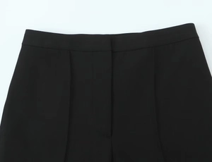 Detail of waist structure and pleats on black casual stirrup pants with elastic waistband
